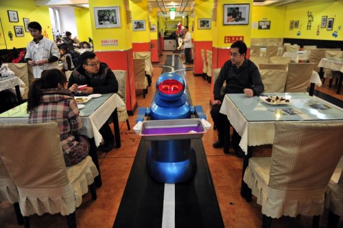 Robot that specialises in delivering food holds an empty plate after serving meals to customers at a Robot Restaurant in Harbin